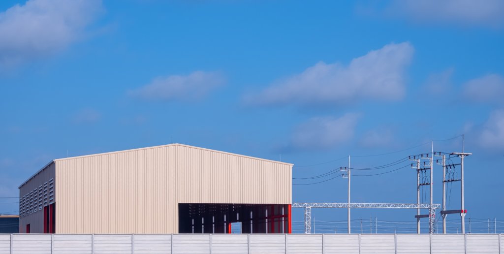 Workshop building with precast concrete fence wall and electric poles against blue sky background